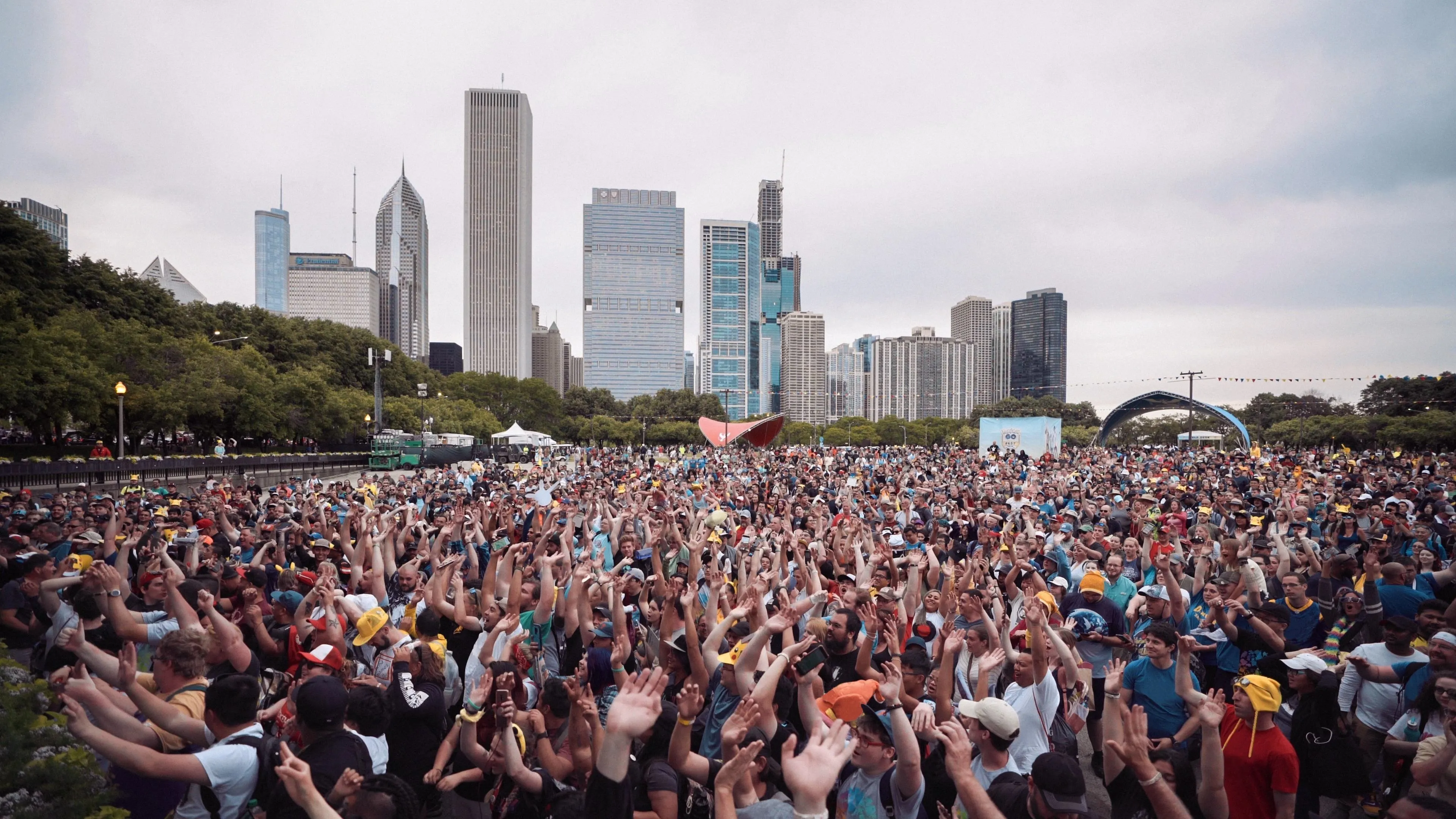 Crowd of people with raised hands, city skyline in the background.